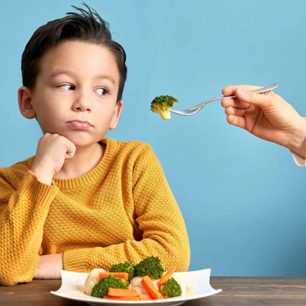 A boy being fed vegetables